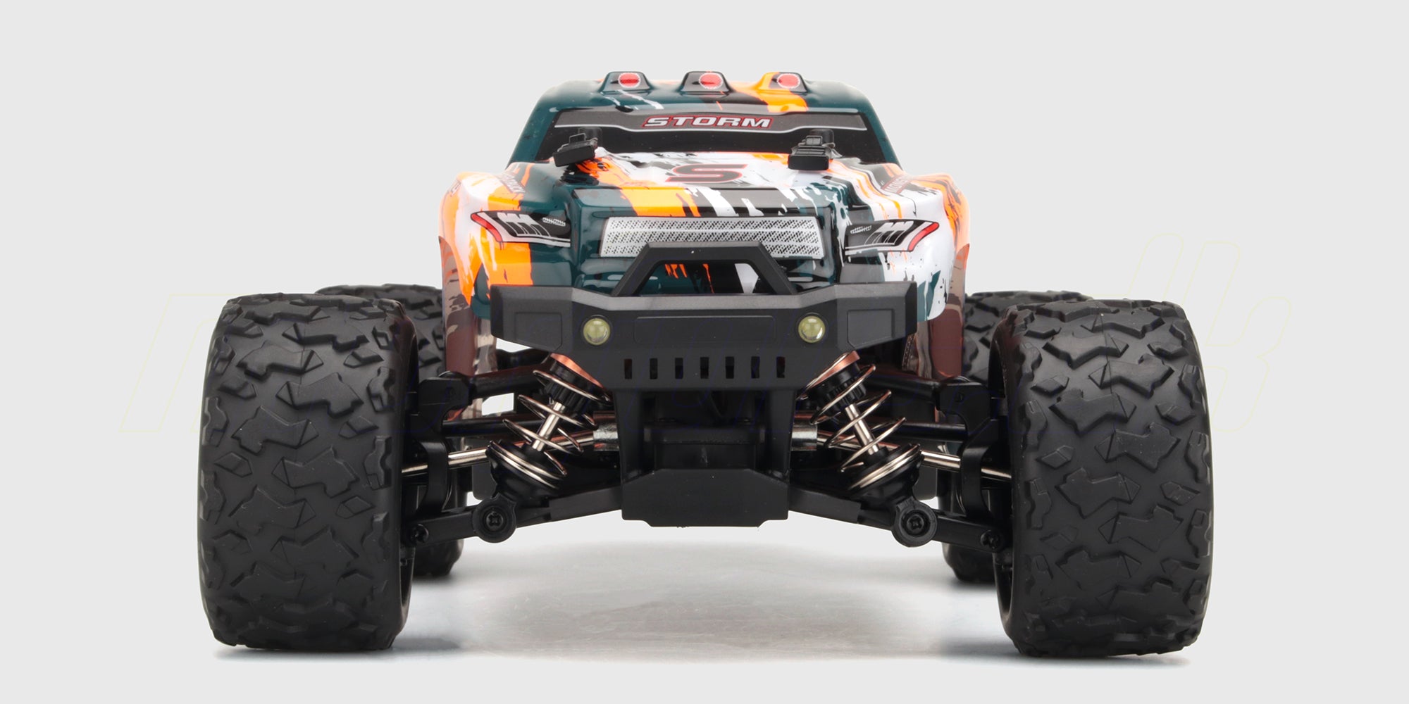 Orange Hurricane 2.0 fjernstyret truck i fuld fart gennem vandpytter med sprøjt på en grusvej.