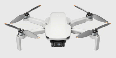 DJI Mini 4K Fly More Combo med drone, fjernkontrol, ekstra batterier og taske vist på hvid baggrund.