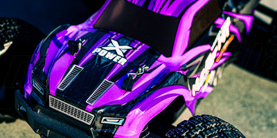 Lilla Hunter MT10 monster truck i aktion på en grusvej omgivet af natur.