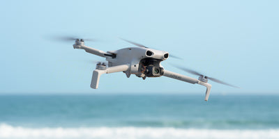 DJI Lito X1 flyver lavt over havet med synligt 4K-kamera og propellerne i bevægelse