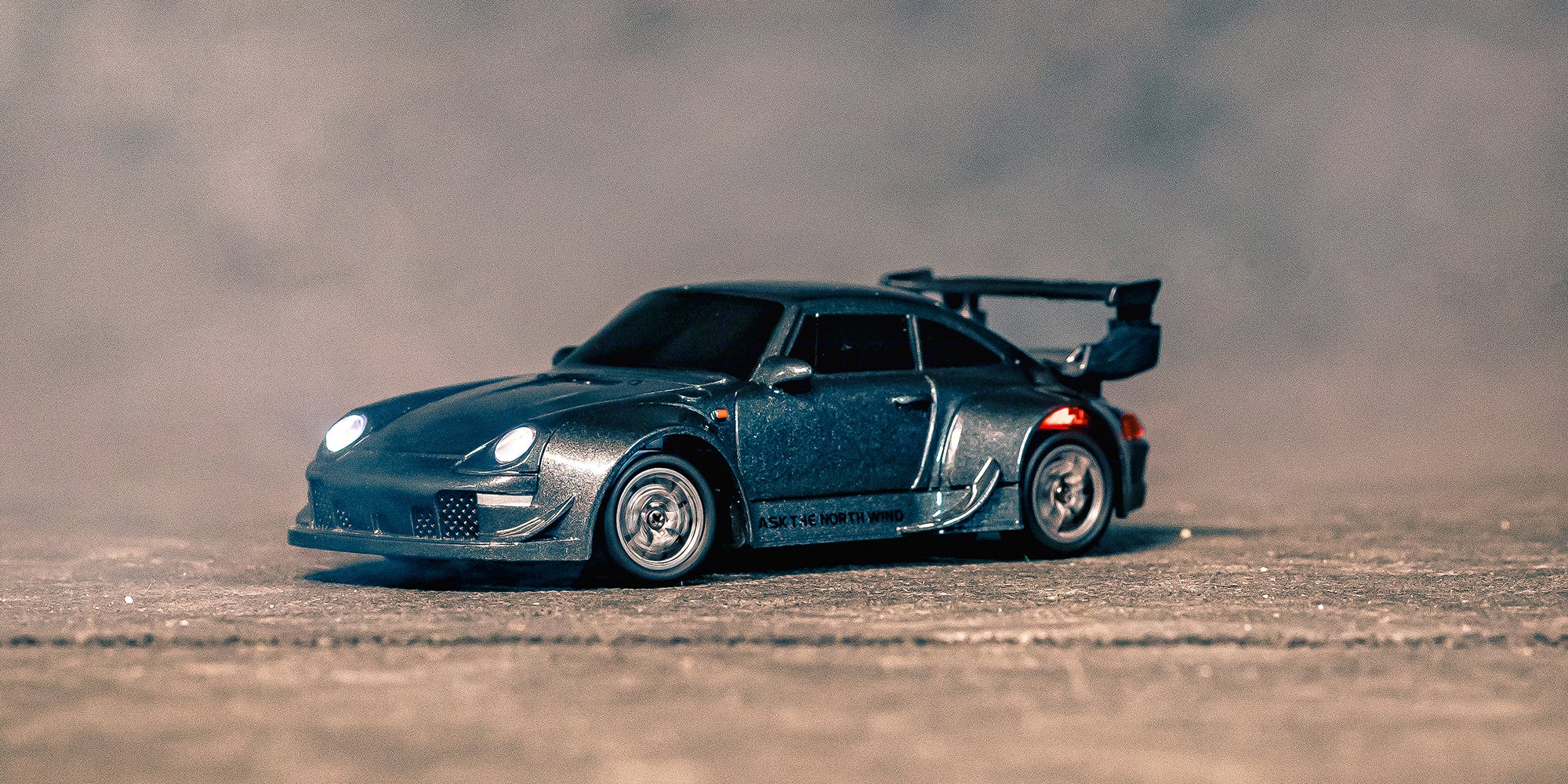 Den grå Mini BTD drifter med hjulspin og forlygterne tændt 