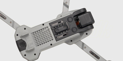 Grå Drone Recon XV1 set nedefra med foldbare arme og rotorblade mod en hvid baggrund.