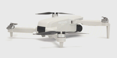 Hvid Drone Recon XV1 med kamera og foldbare arme vist fra siden mod en lys baggrund.