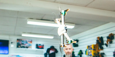 Sort Drone ST16B med propelbeskyttere i luften klar til at lave loops udendørs.