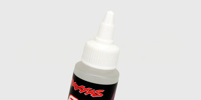 Gennemsigtig flaske med silikoneolie til smøring af støddæmpere på en fjernstyret bil.