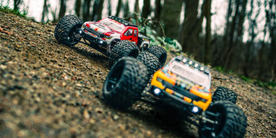 Sort Tornado Brushless monster truck i fuld fart på en grusvej med støvskyer bag de store hjul.