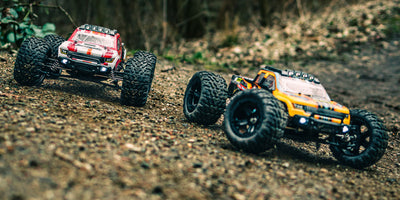 Tornado Brushless fjernstyret bil i fuld fart gennem græs og grus med opsprøjtende støv i naturen.