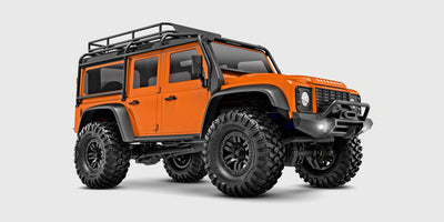 Orange Traxxas TRX-4M Defender crawler i 1:18 skala set fra siden på en hvid baggrund.