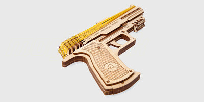 Mekanisk byggesæt i træ af en realistisk Ugears handgun med detaljerede tandhjul og gummibåndsmekanisme.