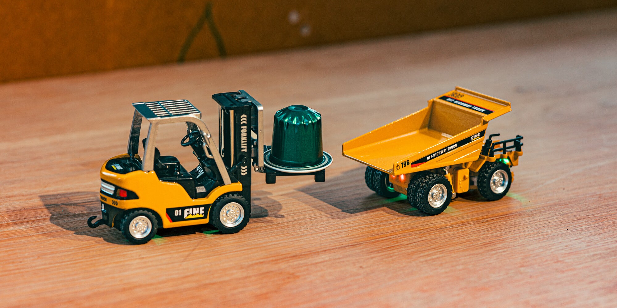 Gul Mini Engineering Car gaffeltruck løfter en kaffekapsel ved siden af dumper