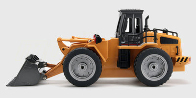 Gul fjernstyret gummiged med bevægelig skovl og sorte hjul på hvid baggrund.