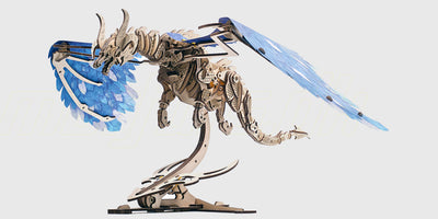 Mekanisk byggesæt af en detaljeret drage i lyst træ med bevægelige vinger og tandhjul.